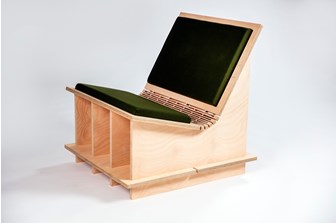 A plywood chair with a green cushion. The wood is laser-cut and bent to create a shallow curve