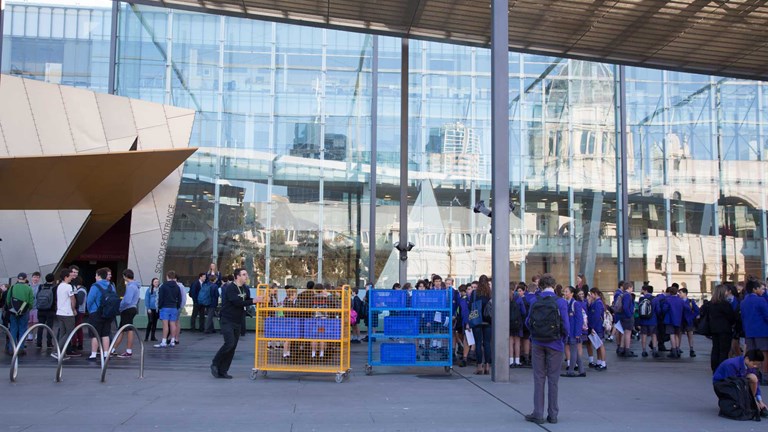 Lots of school students and trolleys on the Melbourne Museum plaza