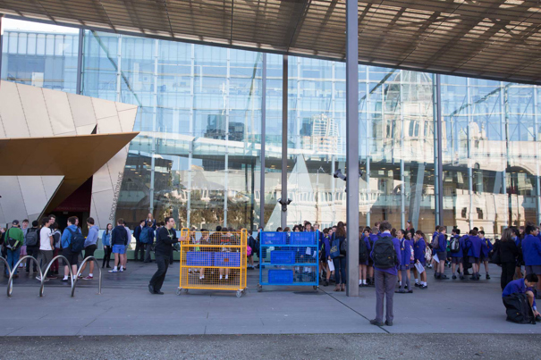 Lots of school students and trolleys on the Melbourne Museum plaza