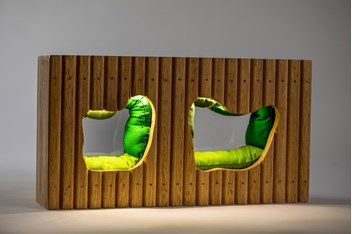 Close-up of a miniature model, two green cushioned enclaves in a wooden wall