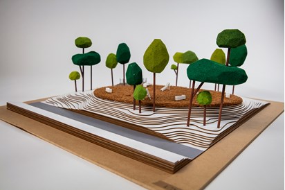 A 3D printed wooden diorama of a small park and playground including topography