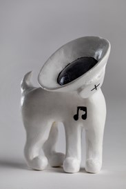 Close-up of a white clay model dog, the head of which has been replaced with a speaker