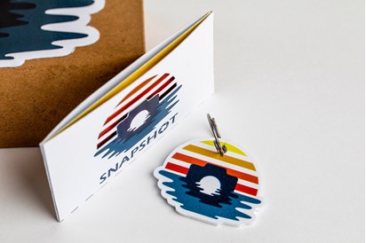 Keyring of a colourful sunset graphic and business card case with the same graphic