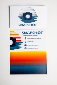 A business card case with a camera and water reflection logo, a business card with contact details, and the reverse side with a gradient of sunset colours
