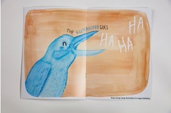 An open picture book for children showing a drawing of a happy blue kookaburra.  Surrounding text reads 'The Kookaburra goes HA HA HA'.