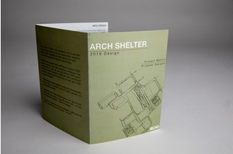 A grey/green promotional leaflet titled 'Arch Shelter' has a black line illustration of the aerial view of a city on the front cover.  Adjacent text reads 'Project Mexico'