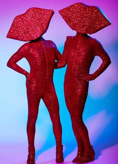 Two figures wearing red sequined full body jumpsuit costumes and heart shaped heads.
