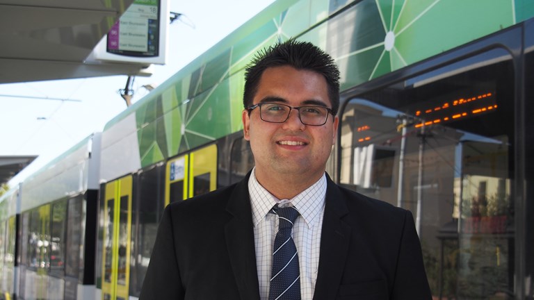Matthew Weston, standing in front of a Melbourne tram