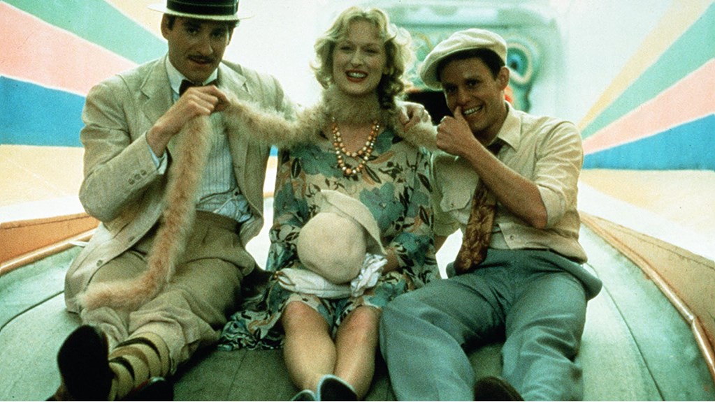 A young Meryl Streep sits between two men. They are all laughing and having fun.