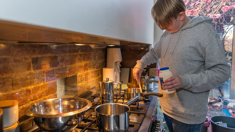 Teenage boy standing at the stove stirring