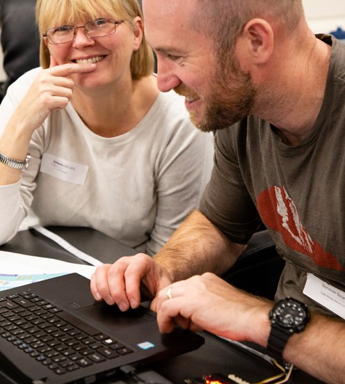 A woman and a man working together in front of a laptop