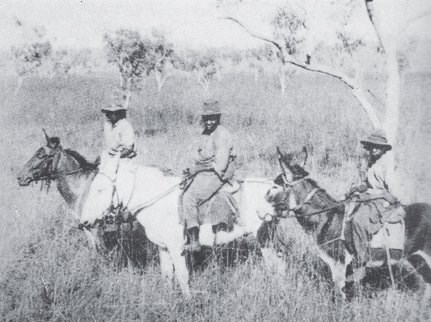 A black and white photograph of three women atop horses.