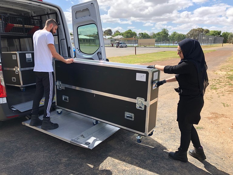 Two Road to Zero teachers unloading a road case from a van