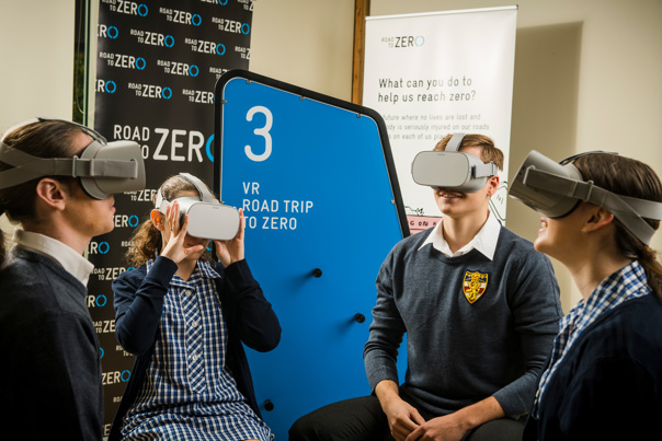 Four students wearing goggles with Road to Zero signage behind them