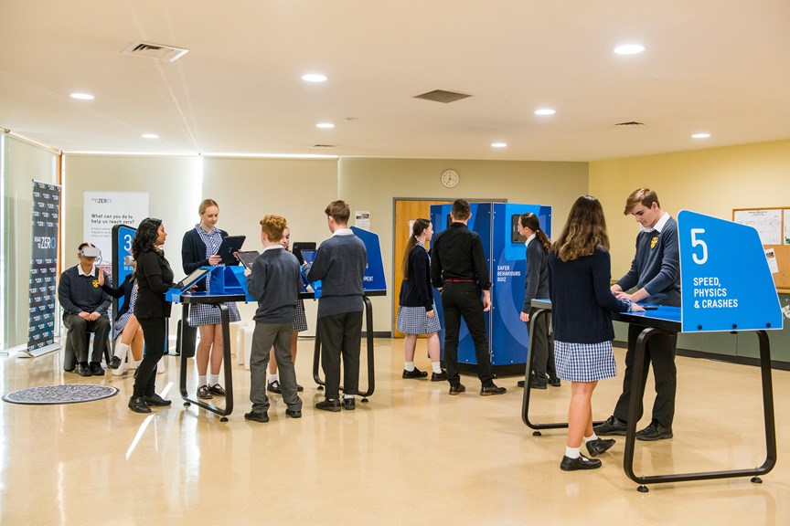 Several students in a room engaging with Road to Zero exhibits