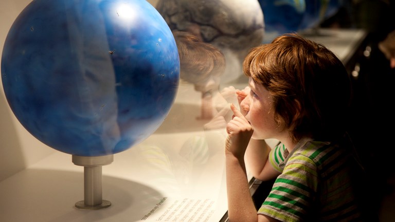 A child looking at Earth globe display 