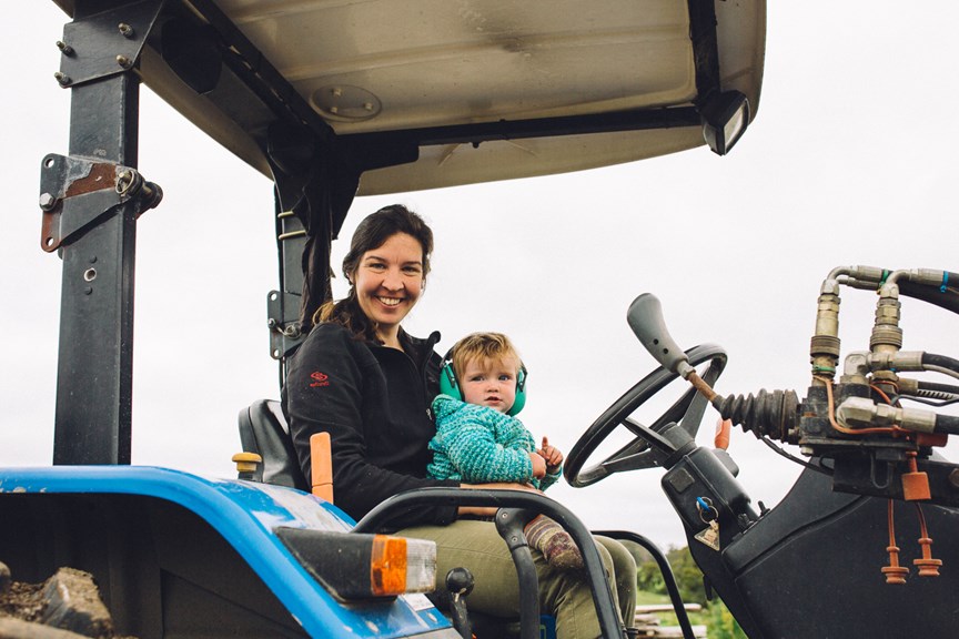 A farmer and her daughter on a tractor.