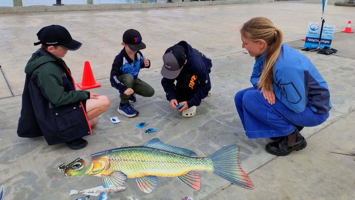 Kids look at some fish art near the beach