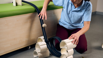 A high school student in a school uniform is dropping a ball on a rubber track model rollercoaster during an education program at Scienceworks.
