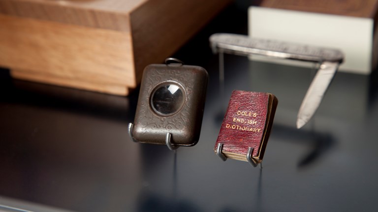 Miniature Cole's English Dictionary with its magnifying case and mini knife on display