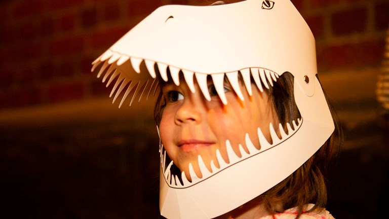 Child wearing a T-Rex mask made of card
