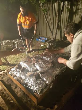 Two men tending and earth oven