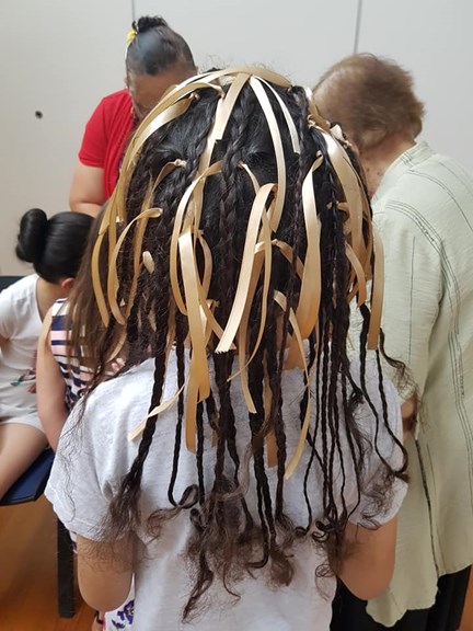 Back of a child's head. Their hair has been braid with ribbons.