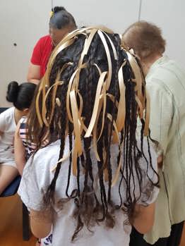 Back of a child's head. Their hair has been braid with ribbons.