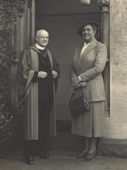 A priest and a woman standing in front of a door way