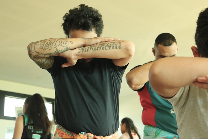 Man standing with his head down and arms crossed in front of him displaying his tattoos