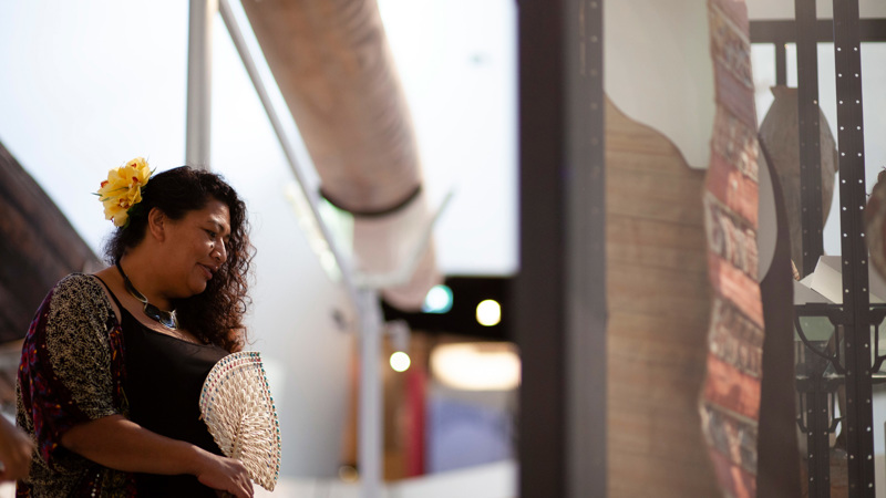 Woman holding a fan, she is viewing an exhibition