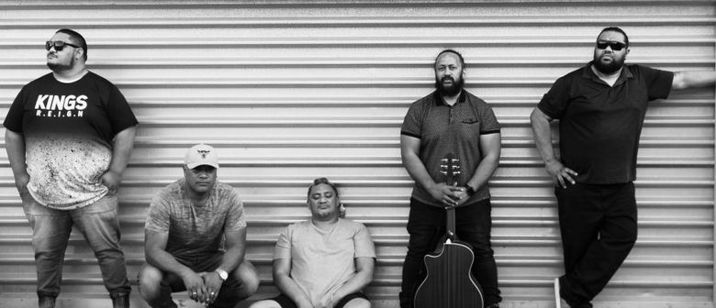 Black and white photo of a group of men one is holding a guitar
