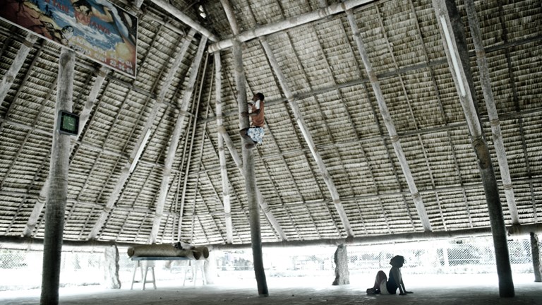 Man climbing a supporting pole to fix the roof