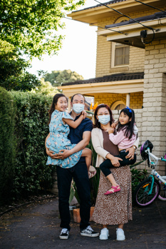 Family of four outside their suburban home. 