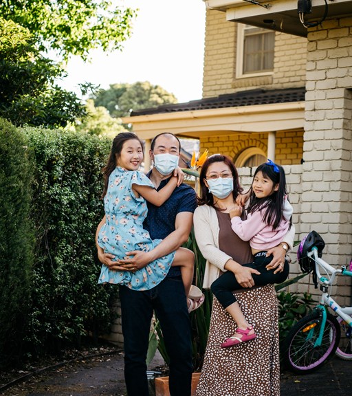Family of four outside their suburban home. 