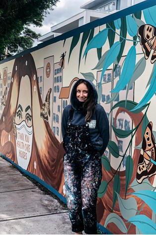Artist in front of a mural
