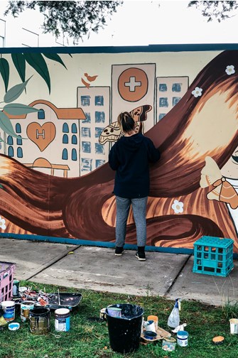Artist painting a mural on a fence