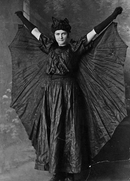 Girl dressed as a bat, arms raised
