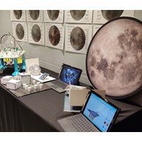 Laptops on a table with diagrams of the moon pinned to the wall behind