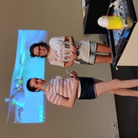 Two students presenting there is a projection behind them