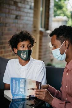 Man and boy in masks reading a book