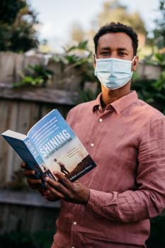 Man wearing a mask holding a book