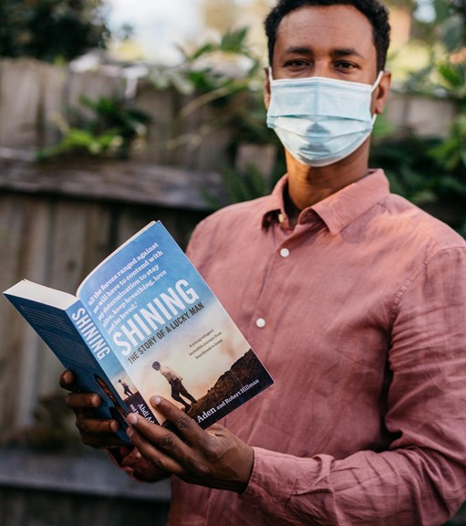 Man wearing a mask holding a book