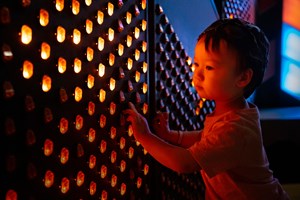 Small child steadying themselves against a wall of lights in the Ground Up exhibition