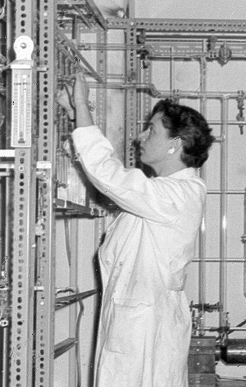 Black and white image of a woman wearing a lab coat in a science lab