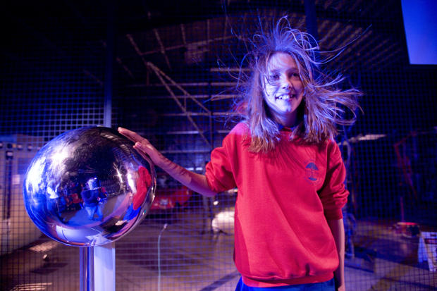 Girl with hand on Van de Graaff generator