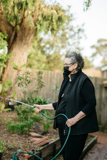 Woman holding a garden hose watering plants