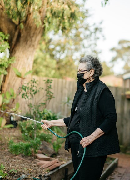 Woman holding a garden hose watering plants