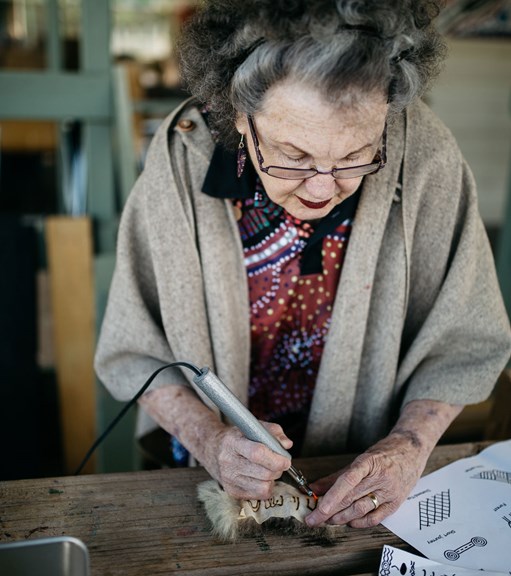 Woman using a tool to engrave possum skin