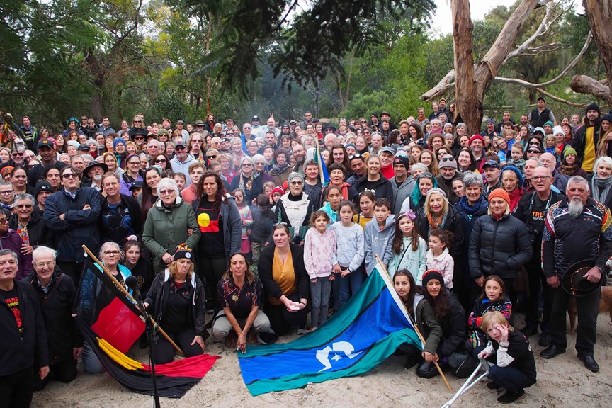 Large group photograph. The Australian Aboriginal and Torres  Strait Island  Flags are being display in front of the group
